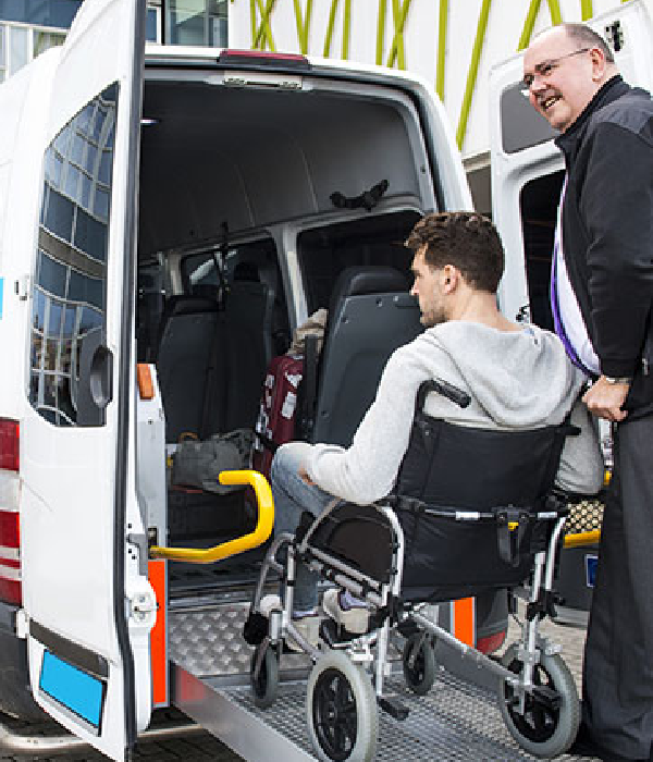 Man in wheelchair being assisted into a medical transport van by a caregiver, highlighting accessible transportation services for non-emergency medical needs.