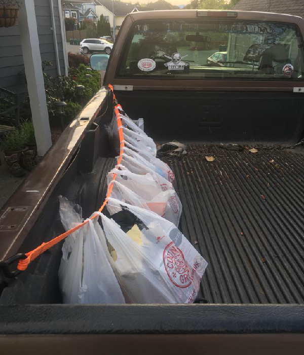 Grocery bags secured in the back of a pickup truck, demonstrating convenient delivery and collection services.